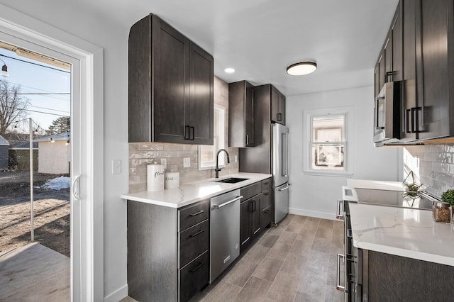 kitchen featuring a sink, stainless steel appliances, plenty of natural light, and baseboards