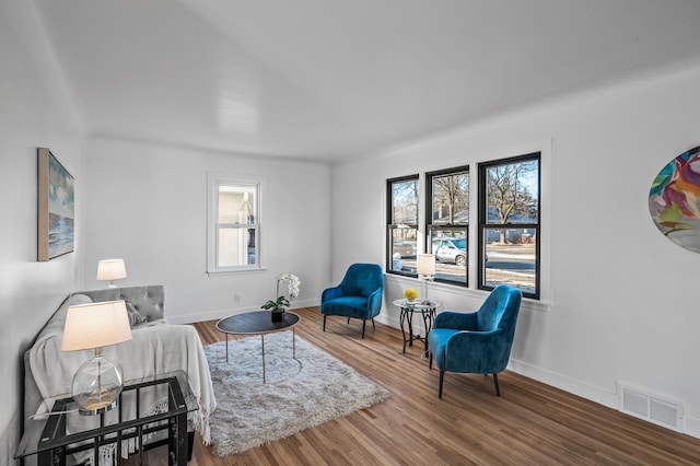 living area with visible vents, baseboards, and wood finished floors