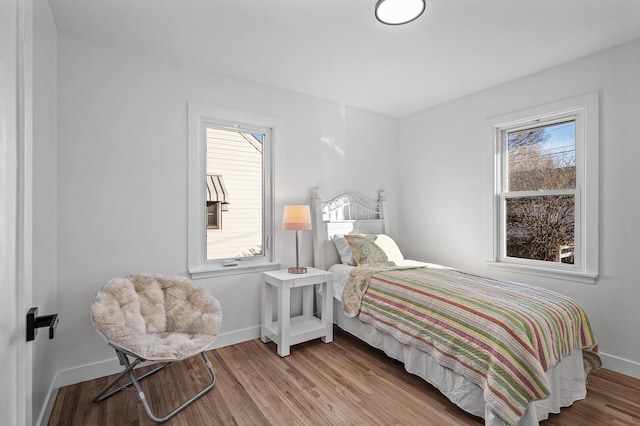 bedroom featuring multiple windows, wood finished floors, and baseboards