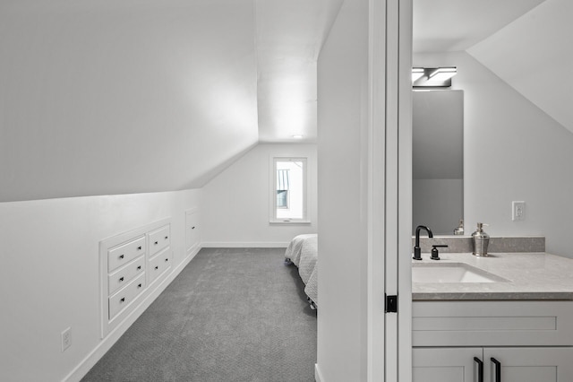 bedroom featuring vaulted ceiling, baseboards, dark colored carpet, and a sink