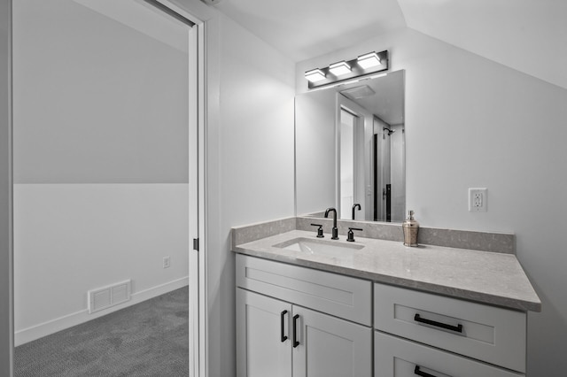 bathroom featuring vanity, lofted ceiling, baseboards, and visible vents