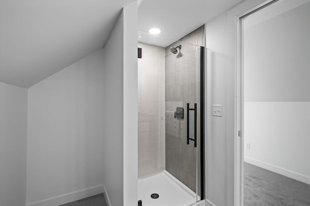 bathroom with a stall shower, baseboards, and vaulted ceiling