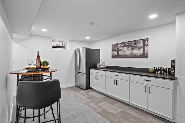 kitchen featuring dark countertops, recessed lighting, white cabinets, and freestanding refrigerator