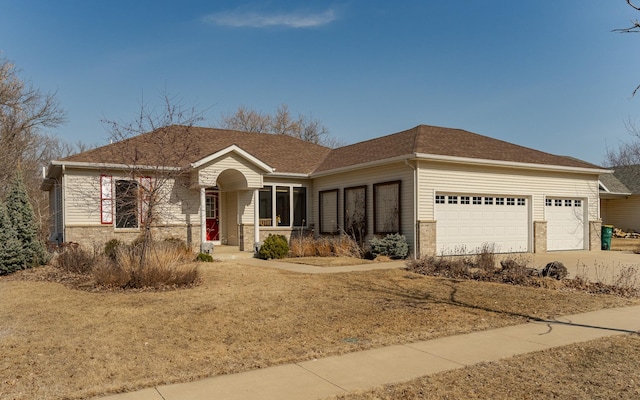 ranch-style house with an attached garage, brick siding, driveway, and roof with shingles