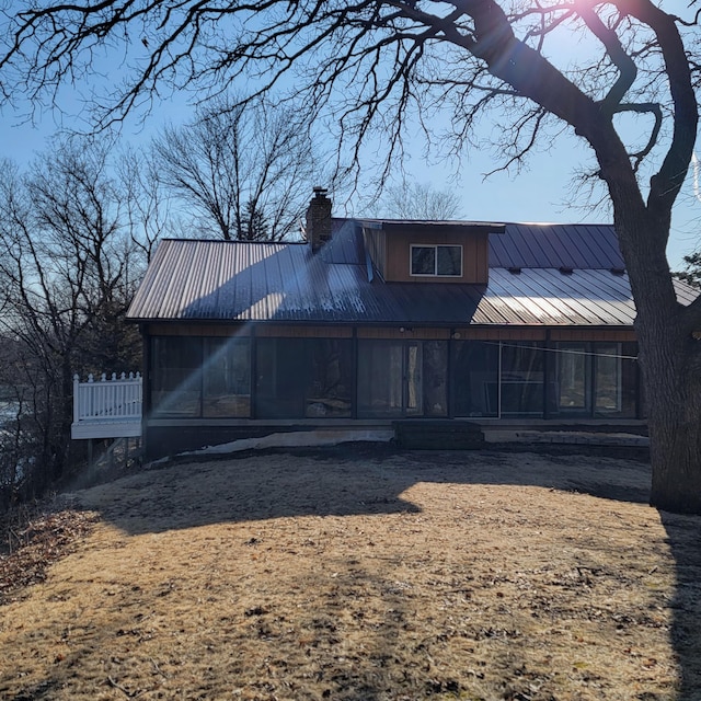 rear view of house featuring metal roof, a chimney, and a sunroom