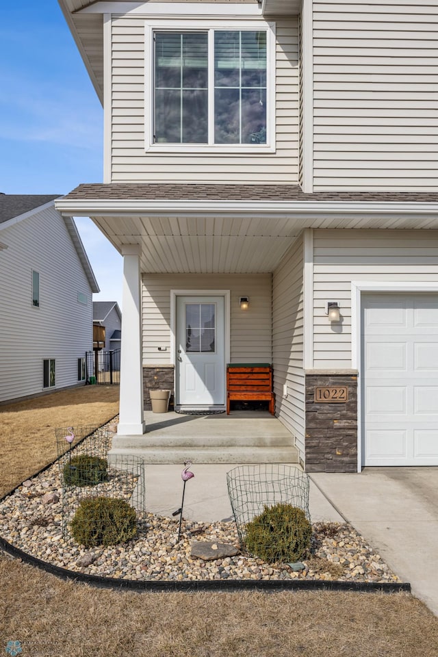 doorway to property featuring a porch, a garage, and a shingled roof