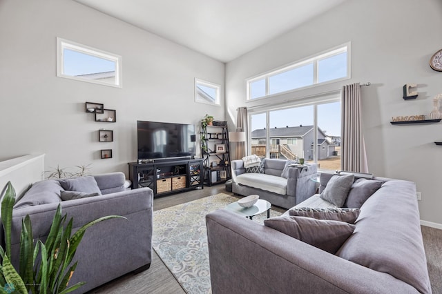 living room featuring baseboards, a towering ceiling, and wood finished floors