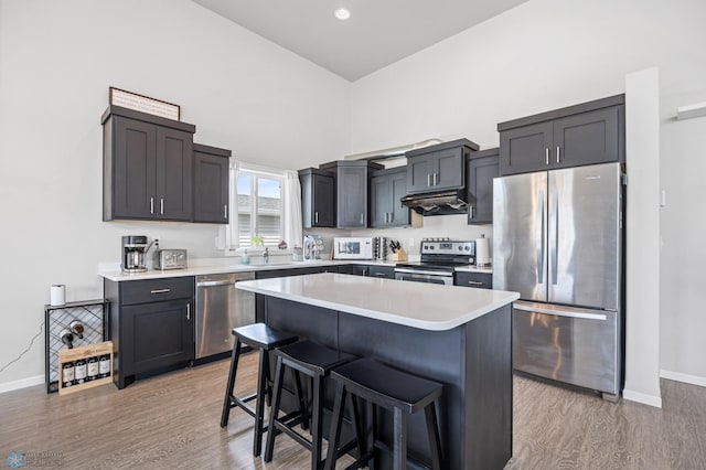 kitchen featuring a kitchen breakfast bar, light wood-type flooring, under cabinet range hood, and stainless steel appliances