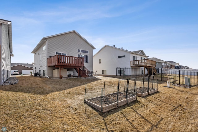 back of property featuring fence, stairway, a yard, a deck, and a garden