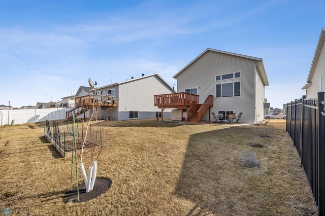 rear view of house with stairway, a wooden deck, a vegetable garden, a fenced backyard, and a lawn