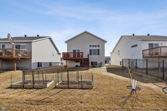 back of house featuring a lawn, fence, a deck, and a garden