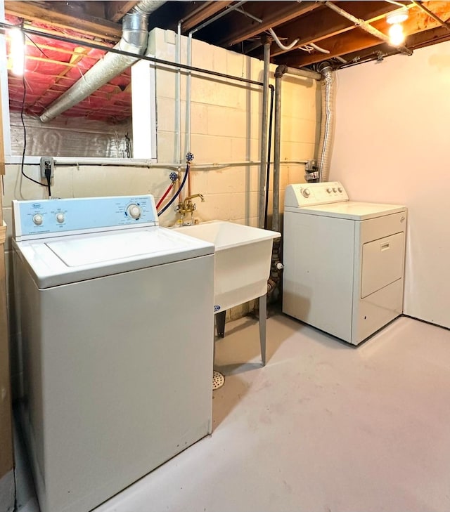 laundry area featuring laundry area, concrete block wall, separate washer and dryer, and a sink