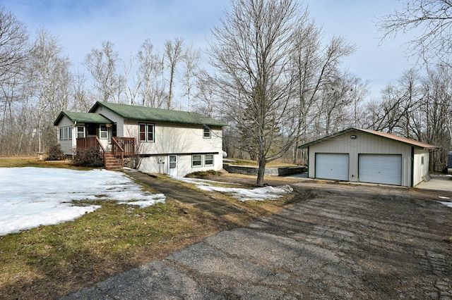 view of snowy exterior featuring an outbuilding, a garage, and driveway