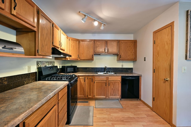 kitchen featuring light wood-type flooring, a sink, black appliances, under cabinet range hood, and brown cabinets