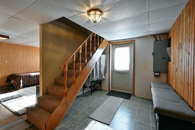 interior space featuring electric panel, wooden walls, and a paneled ceiling