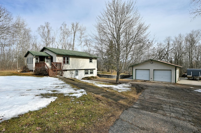 view of snowy exterior featuring a garage and an outbuilding