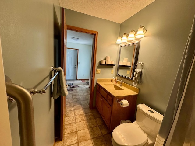 bathroom featuring a textured ceiling, toilet, vanity, and stone finish flooring