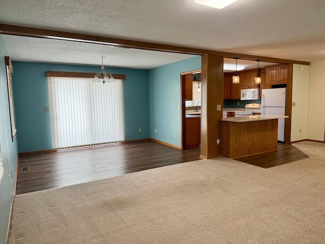 kitchen featuring decorative light fixtures, white appliances, carpet floors, brown cabinetry, and a chandelier