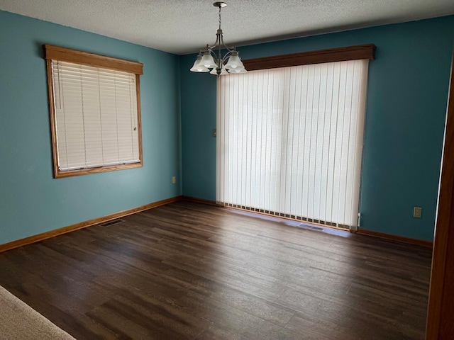 unfurnished room featuring wood finished floors, baseboards, visible vents, a textured ceiling, and a chandelier