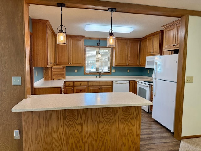 kitchen featuring brown cabinets, white appliances, a peninsula, and a sink