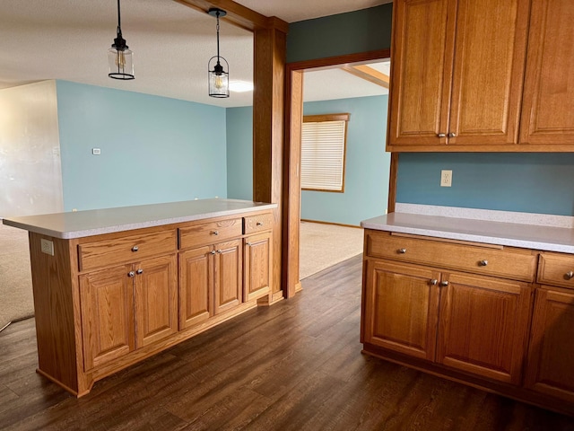 kitchen featuring dark wood finished floors, light countertops, brown cabinets, and pendant lighting