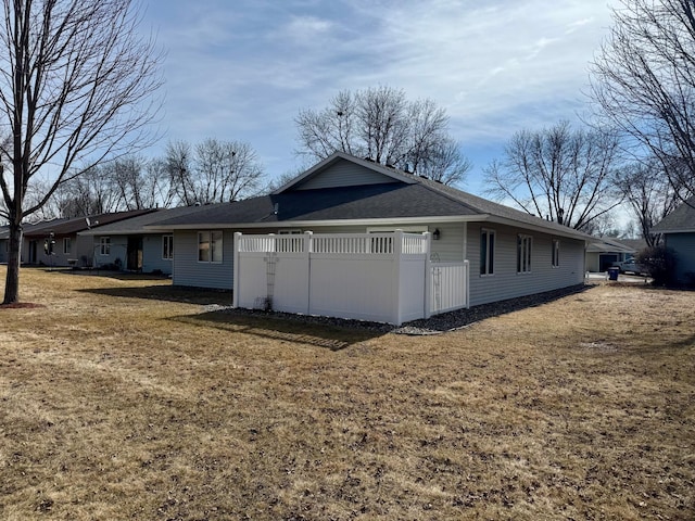 exterior space featuring a yard, fence, and a shingled roof