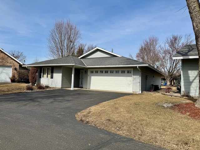 ranch-style home with driveway, roof with shingles, and an attached garage