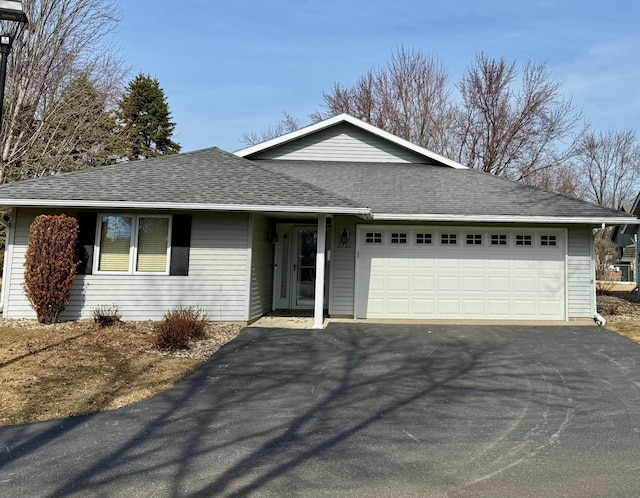 ranch-style home featuring a garage, driveway, and a shingled roof