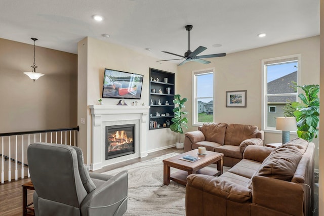6627 133rd St, Savage, MN 55378 - living area featuring wood finished floors, built in shelves, a ceiling fan, a glass covered fireplace, and recessed lighting