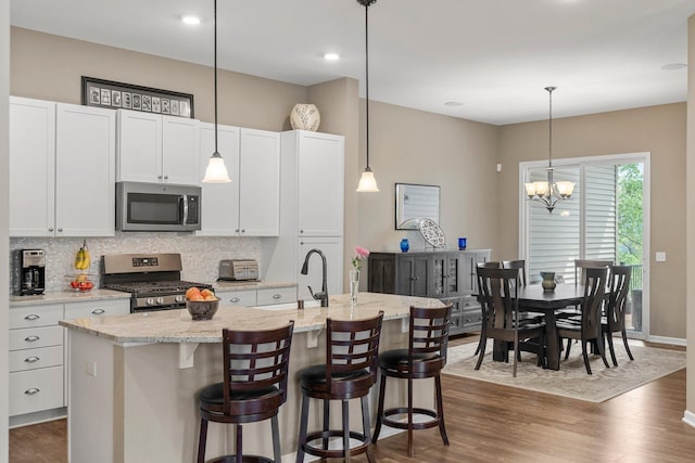 6627 133rd St, Savage, MN 55378 - kitchen with stainless steel appliances, backsplash, a sink, a kitchen island with sink, and white cabinets