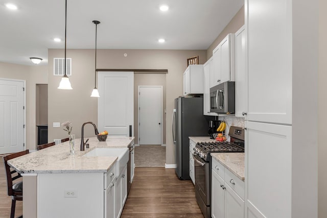 6627 133rd St, Savage, MN 55378 - kitchen with stainless steel appliances, a breakfast bar area, a sink, dark wood finished floors, and recessed lighting
