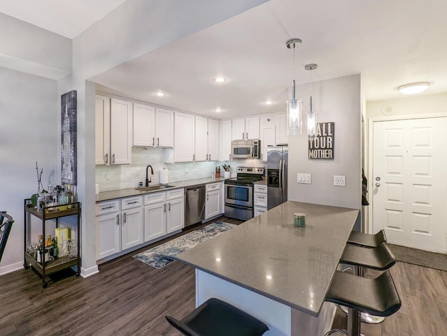 kitchen with a sink, a kitchen breakfast bar, dark wood-style floors, and stainless steel appliances