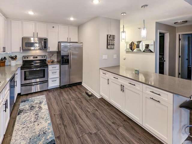 kitchen with a peninsula, recessed lighting, dark wood-style flooring, white cabinets, and appliances with stainless steel finishes