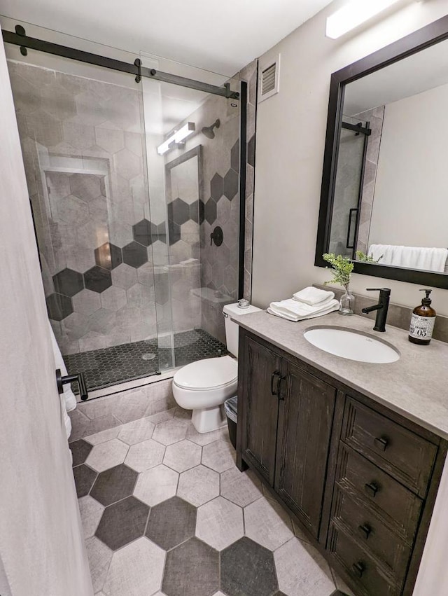 bathroom featuring visible vents, toilet, a stall shower, and vanity