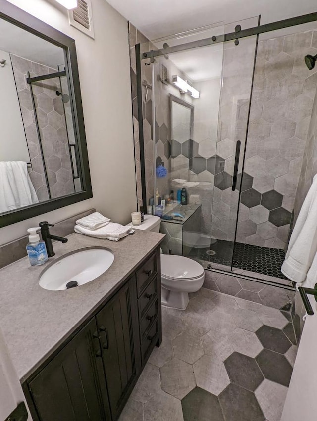 bathroom featuring visible vents, toilet, a stall shower, and vanity