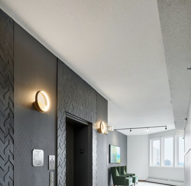 room details featuring elevator, baseboard heating, and rail lighting