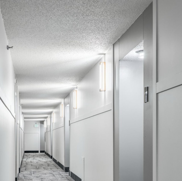 hall featuring a textured ceiling and light wood finished floors