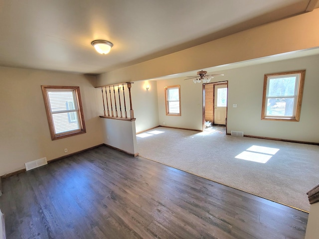 empty room with visible vents, ceiling fan, baseboards, and wood finished floors