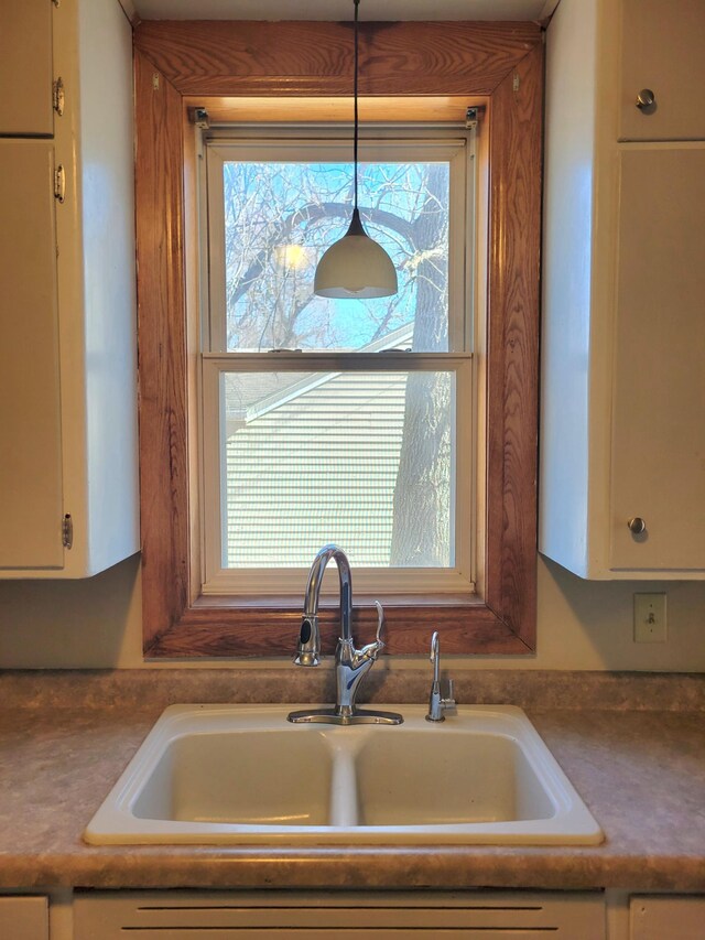 details featuring decorative light fixtures, white cabinets, and a sink