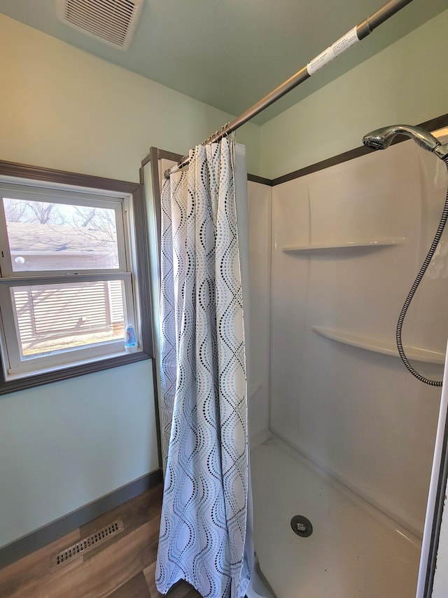 bathroom featuring wood finished floors, visible vents, and a stall shower