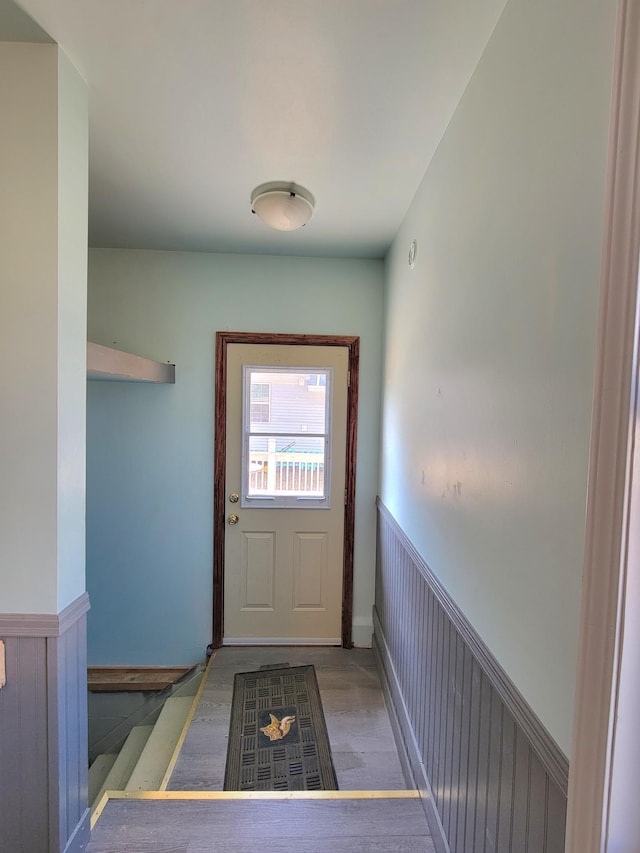 doorway to outside featuring wainscoting and wood finished floors