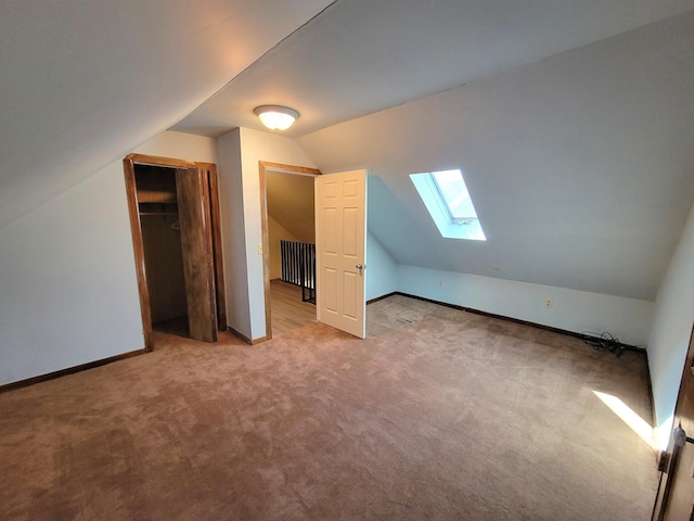 additional living space featuring carpet flooring, vaulted ceiling with skylight, and baseboards