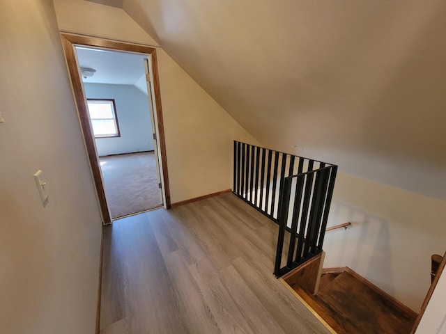 stairs with baseboards, lofted ceiling, and wood finished floors