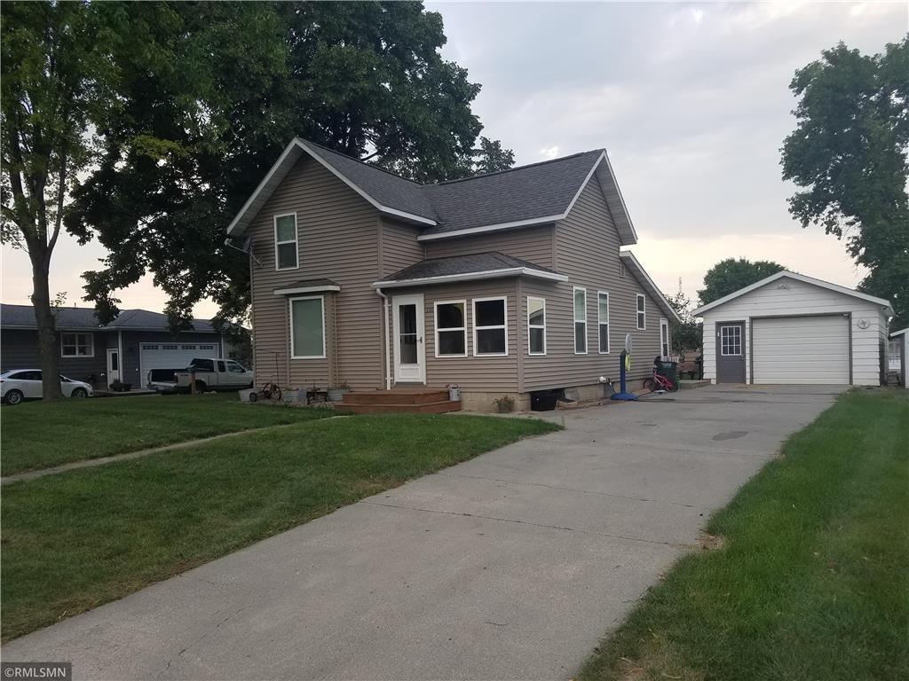 view of front of house featuring a yard, a detached garage, an outdoor structure, and a shingled roof