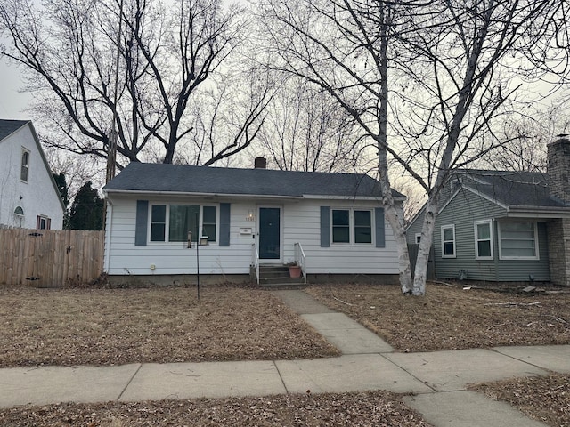 view of front of home with entry steps, fence, and a chimney