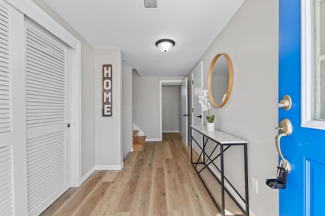 hallway with stairs, baseboards, visible vents, and light wood finished floors