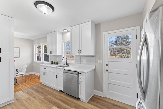 kitchen with a sink, stainless steel appliances, light wood-style floors, and white cabinets