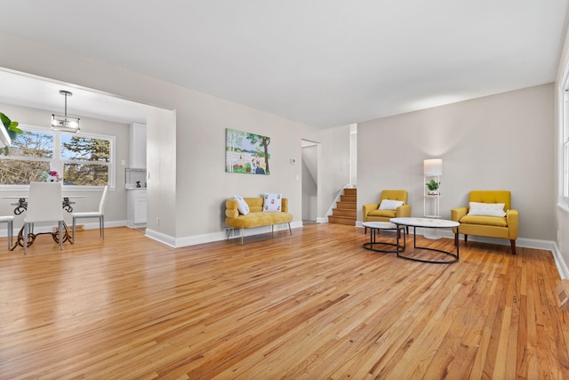 living area featuring stairway, light wood-style flooring, and baseboards