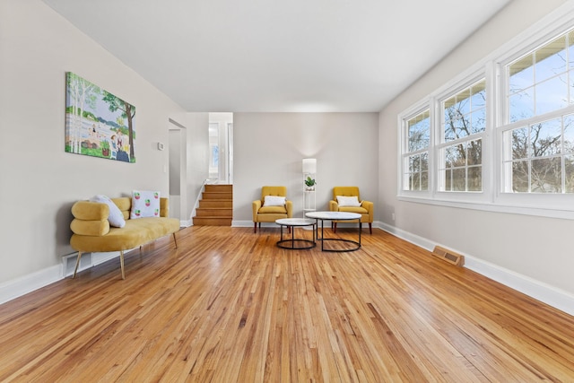 living area featuring visible vents, light wood-style flooring, and baseboards