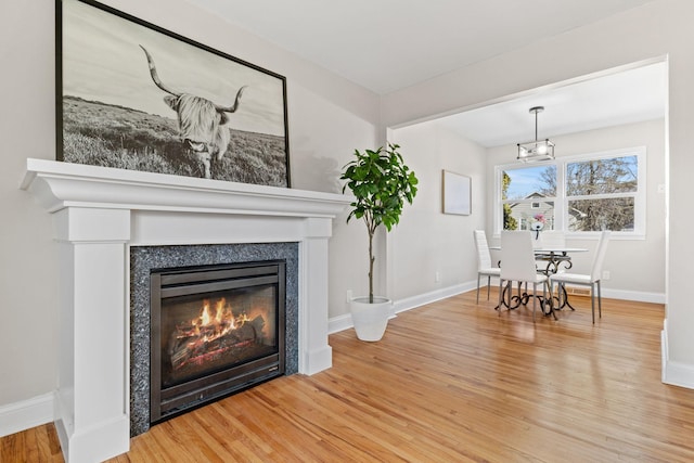 interior space featuring a glass covered fireplace, baseboards, and wood finished floors